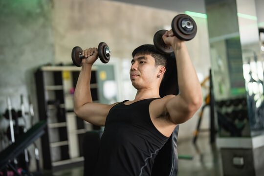 Athlete executing seated dumbbell shoulder press in a gym, focusing on upper body strength, showcasing one of the best shoulder exercises.