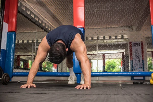 A young man doing pike pushups in a gym in order to workout the shoulders