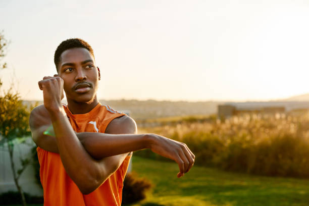 Man doing a cross-body shoulder stretch in an outdoor setting.