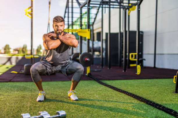 Young male athlete exercising at the gym. He is doing squats workout at the health club.