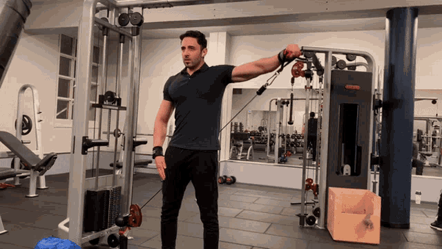 Athlete engaged in cable lateral raises at a fitness center, isolating the medial deltoids, key for achieving broad shoulders in a strength training session.