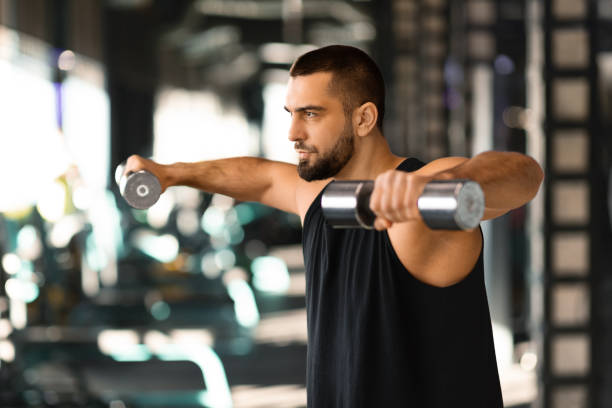 Fitness enthusiast doing dumbbell lateral raises to enhance shoulder width, demonstrating proper form in one of the best shoulder exercises for mass.