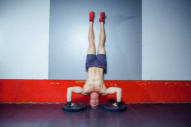 Athlete performing handstand pushups against a wall, an advanced bodyweight shoulder exercise.