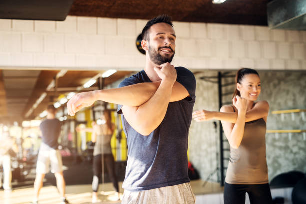 Man performing a shoulder warm-up routine before a workout, vital for preventing injuries.