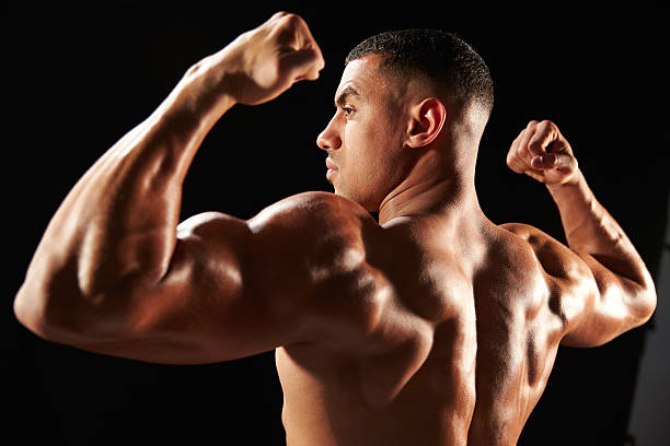 Male bodybuilder flexing muscles, side view