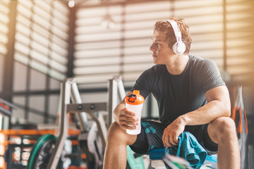 Portait of tired athletic man relaxing and drinking pre-workout drink from a classic fitness shaker. Horizontal shot Stock Photo | Adobe Stock